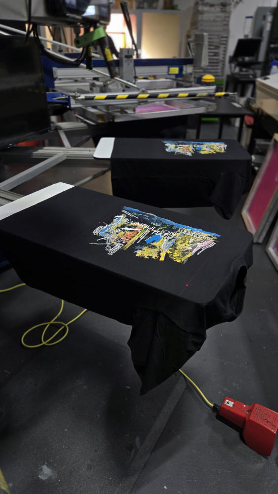 Embroidery machine mid-stitch on a row of teal caps