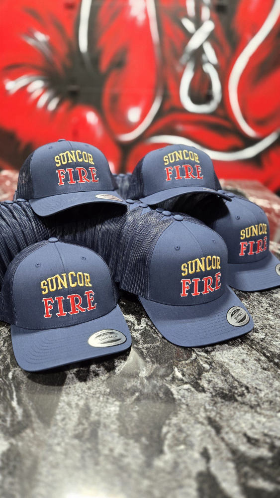 Stack of embroidered navy Suncor Fire trucker hats