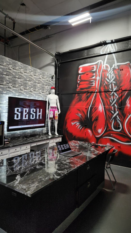 Shop display corner with boxing glove mural and branded gear