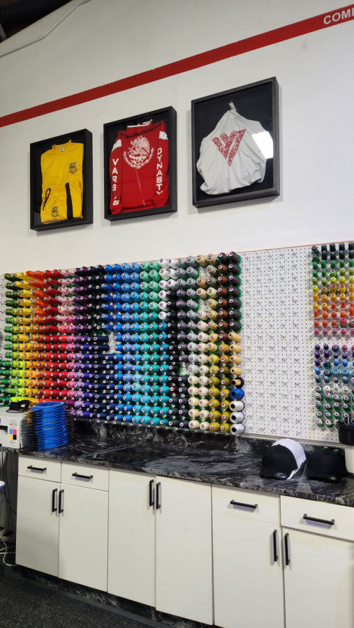 Wall of embroidery thread spools and framed custom garments